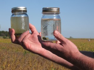 Ohio farmer Jeff Rasawehr, a 2009 SARE grantee, illustrates cover crops’ role in protecting water quality. The jar on the right holds runoff from a cover-cropped field; on the left is runoff from a non-cover-cropped field.  Photo credit: Sean McGovern, SARE Outreach