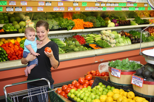 Young mother with child selects items in produce aisle of grocery store. Photo credit: USDA.
