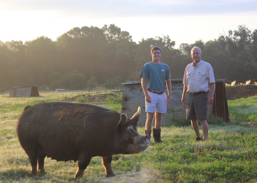 Thompson Farms owner Andrew Thompson and son Bayly with their “happy, healthy hogs.” Photo Credit: Thompson Farms